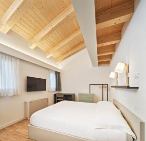 a bedroom with a white bed and wooden ceilings at Crocevia - Locanda carsica contemporanea in Trieste
