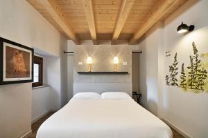 a bedroom with a white bed with two lights at Crocevia - Locanda carsica contemporanea in Trieste