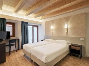 a bedroom with a large white bed and a desk at Crocevia - Locanda carsica contemporanea in Trieste