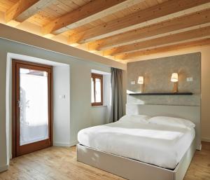 a bedroom with a large white bed and a window at Crocevia - Locanda carsica contemporanea in Trieste