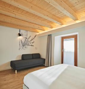 a bedroom with a bed and a couch at Crocevia - Locanda carsica contemporanea in Trieste