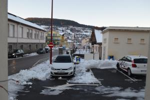 una macchina bianca parcheggiata in un parcheggio con neve di Hôtel Timgad a Gérardmer