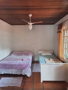 a bedroom with two beds and a ceiling fan at Leal house in Matinhos