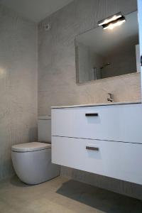 a bathroom with a sink and a toilet and a mirror at Moderne Ferienwohnung Primavera in Colonia Sant Jordi