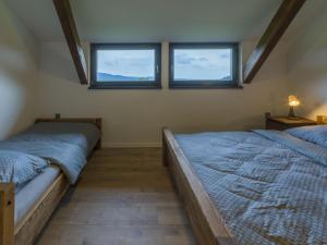 two beds in a room with two windows at Apartmán pod Pustým vrchem in Říčky