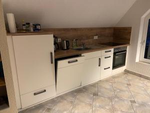 a kitchen with white cabinets and a sink at Ferienhaus Harzvorland in Ballenstedt