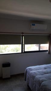 a bedroom with a bed and two windows in it at Maganal in Villa Carlos Paz