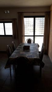 a dining room table with chairs in a room with windows at Maganal in Villa Carlos Paz