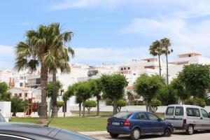two cars parked in a parking lot with palm trees at Apartamento Verano in Conil de la Frontera