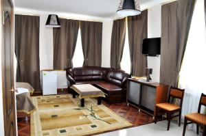 a living room with a leather couch and a television at Hotel Vostok in Sorochinsk