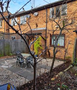 ロンドンにあるSW19 - Quiet split-level 2-bedroom maisonette with gardenのベンチと木が目の前にある家