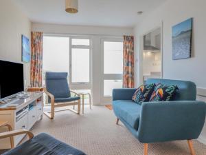 a living room with a blue couch and a tv at 48 Glan Y Mor in Fairbourne