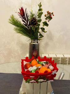 a red basket of fruit on a table with a vase at Dina Lux Iasi Apartment in Iaşi