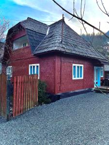 a red house with a fence in front of it at Casa Fântâna - La poalele muntilor -50 de metri de pârtia Olimpică in Statiunea Borsa