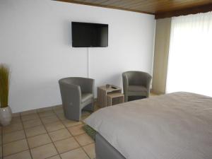 a bedroom with a bed and two chairs and a tv at Gästehaus Lohmann in Bullay