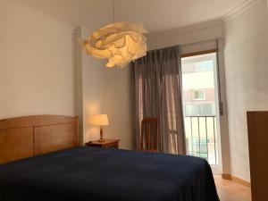 um quarto com uma cama e um lustre em Monte Gordo Beach Flat with Balcony em Monte Gordo