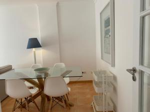 uma sala de jantar com uma mesa de vidro e cadeiras brancas em Monte Gordo Beach Flat with Balcony em Monte Gordo