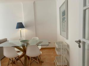 a dining room with a glass table and white chairs at Monte Gordo Beach Flat with Balcony in Monte Gordo