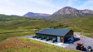 una casa su una collina con montagne sullo sfondo di Kinloch Ainort Apartments a Luib