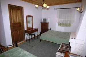 1 dormitorio con 2 camas, espejo y escritorio en Terpsichori Guesthouse, en Kapesovo