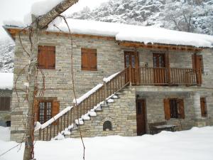 una casa de piedra con una escalera en la nieve en Terpsichori Guesthouse, en Kapesovo
