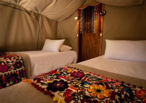 ein Zimmer mit 2 Betten und einer Decke darauf in der Unterkunft Glamping Chaska Ocupi in Urubamba