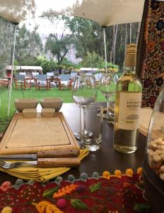 a table with a bottle of wine and glasses at Glamping Chaska Ocupi in Urubamba