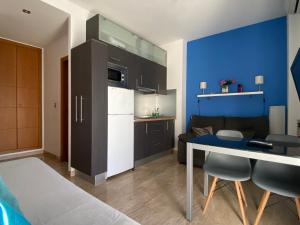 a small kitchen and living room with a blue wall at Studio City Center - Aloha Sevilla in Seville