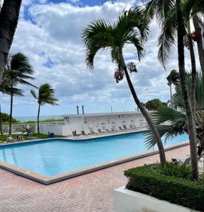 a swimming pool with palm trees in front of a building at CASABLANCA -Kitchen, Pool, Beach- in Miami Beach