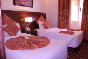 a hotel room with two beds with white sheets at Amra Palace International Hotel in Wadi Musa