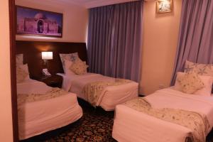 a hotel room with three beds and a mirror at Amra Palace International Hotel in Wadi Musa