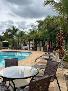 um pátio com uma mesa e cadeiras ao lado de uma piscina em Confraria Colonial Hotel Boutique em Mairinque