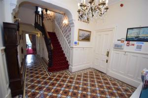 a hallway with a staircase in a house with a chandelier at Three Gables in Bridlington