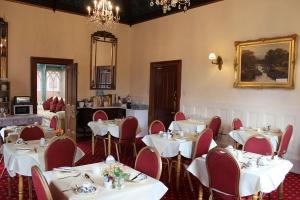 un comedor con mesas blancas y sillas rojas en Three Gables en Bridlington