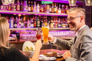 un homme et une femme assis dans un bar en train de boire de la bière dans l'établissement Le Noranda Hotel & Spa, Ascend Hotel Collection, à Rouyn-Noranda