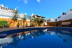 una gran piscina con un columpio frente a un edificio en Coco Surfhouse - Coworking Coliving, en Corralejo