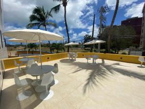 a patio with tables and chairs and umbrellas at Flat - Victory Intermares in Cabedelo