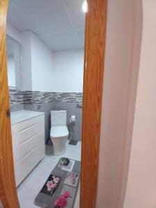 een badkamer met een toilet en een mat op de vloer bij Julia's Paradise Apartment in Torrevieja
