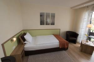 a bedroom with a bed and a desk and a chair at Landhotel Zum Hasen Hein in Hamminkeln
