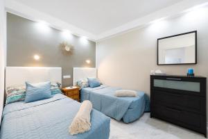 a bedroom with two beds and a dresser with a mirror at PARADISE VIEW APARTMENT MASPALOMAS in Maspalomas +20 photos