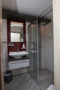 a bathroom with a sink and a glass shower at Landhotel Zum Hasen Hein in Hamminkeln