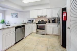 una cocina con armarios blancos y electrodomésticos de acero inoxidable en The Waterman's Retreat Unit N, en Fort Lauderdale