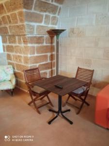 einem Holztisch mit zwei Stühlen und einer Lampe in der Unterkunft La conigliera in Brindisi