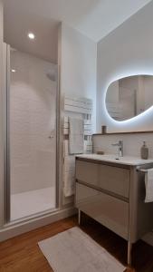 La salle de bains blanche est pourvue d'une douche et d'un lavabo. dans l'établissement Au 53, sous le chartil, à Reims