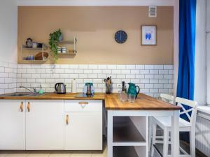 una cucina con armadi bianchi e ripiano in legno di Silent blue apartment / Kochanowskigo St a Cracovia