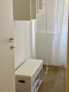 uma casa de banho branca com um banco branco e uma janela em Vivapartments MilanoSanSiro em Milão
