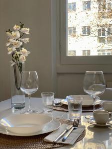 a table with two wine glasses and a vase of flowers at Vivapartments MilanoSanSiro in Milan