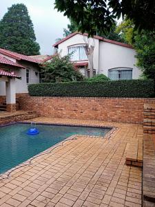 uma parede de tijolos e uma piscina em frente a uma casa em Friends Place em Joanesburgo