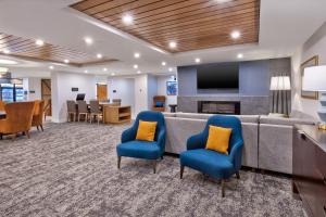 - une salle d'attente avec un canapé, des chaises et une télévision dans l'établissement Staybridge Suites Pittsburgh Airport, an IHG Hotel, à Pittsburgh
