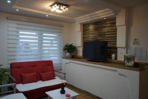 sala de estar con silla roja y TV de pantalla plana en Apartman Volijak, en Jajce